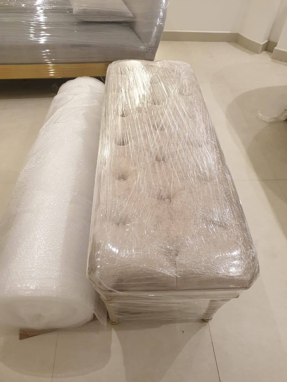 كنبة مغلفة بالبلاستيك بجانب رول فقاعات هوائية للتغليف